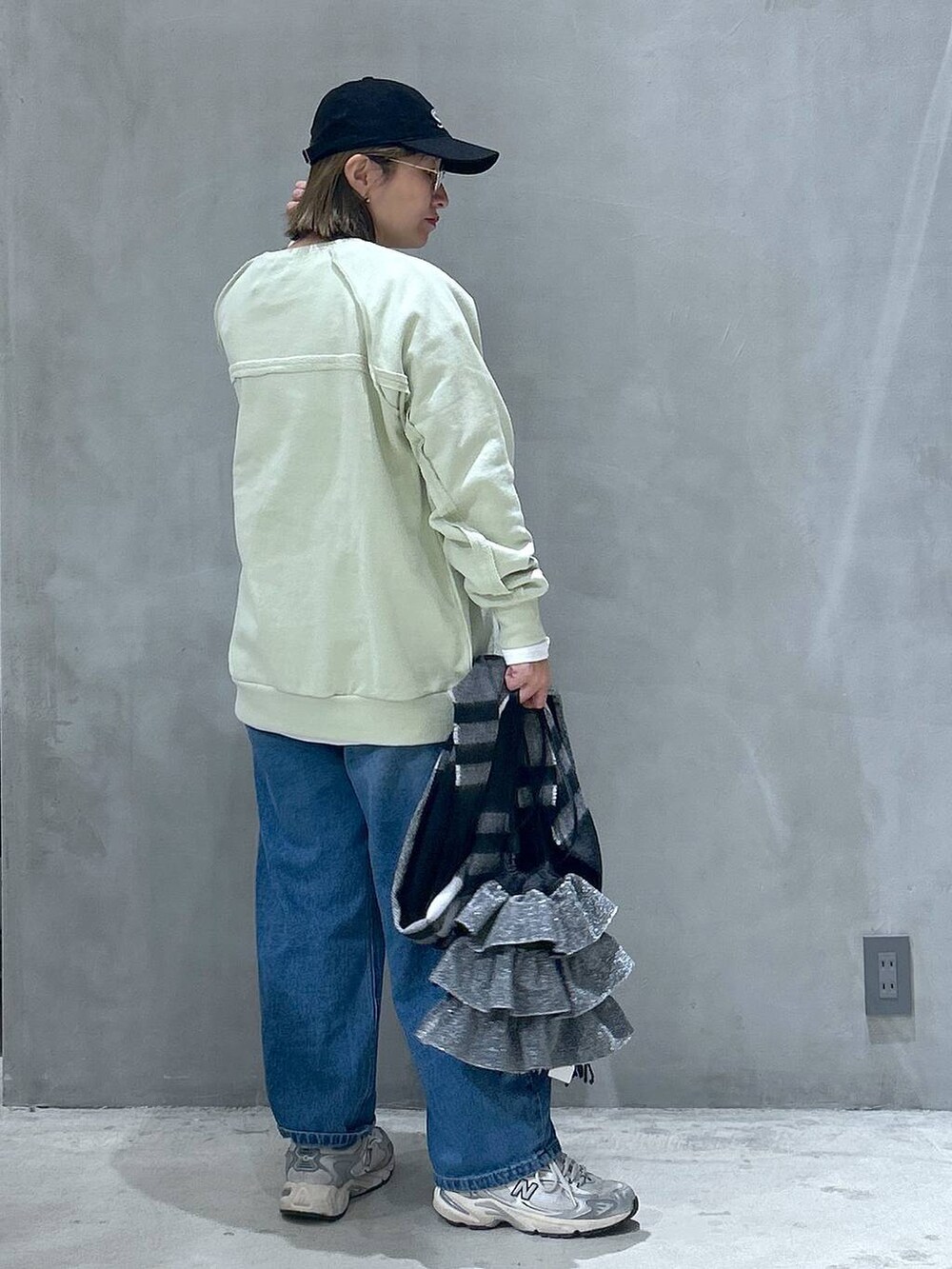 ブルー系のデニムパンツ、シルバー系のショルダーバッグ、グリーン系のスウェットを着用したレディースの冬コーディネートの4枚目の写真
