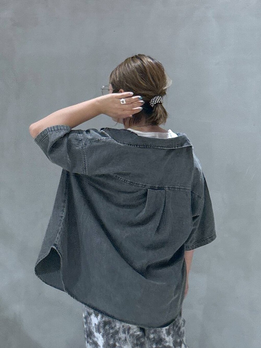 ブラック系のショルダーバッグ、ブラック系のスニーカー、ブルー系のシャツ/ブラウスを着用したレディースの夏コーディネートの3枚目の写真