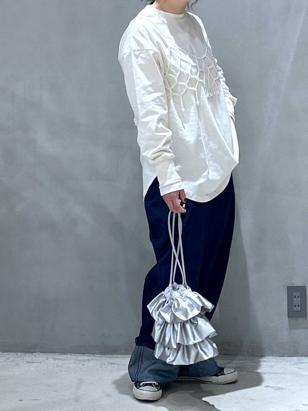 ホワイト系のベスト、シルバー系のショルダーバッグ、ブルー系のデニムパンツを着用したレディースの冬コーディネートの3枚目の写真