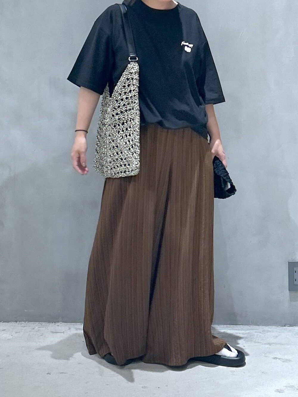 ブラック系のトートバッグ、ブラック系のサンダル、ブラウン系のその他パンツを着用したレディースの春コーディネートの6枚目の写真