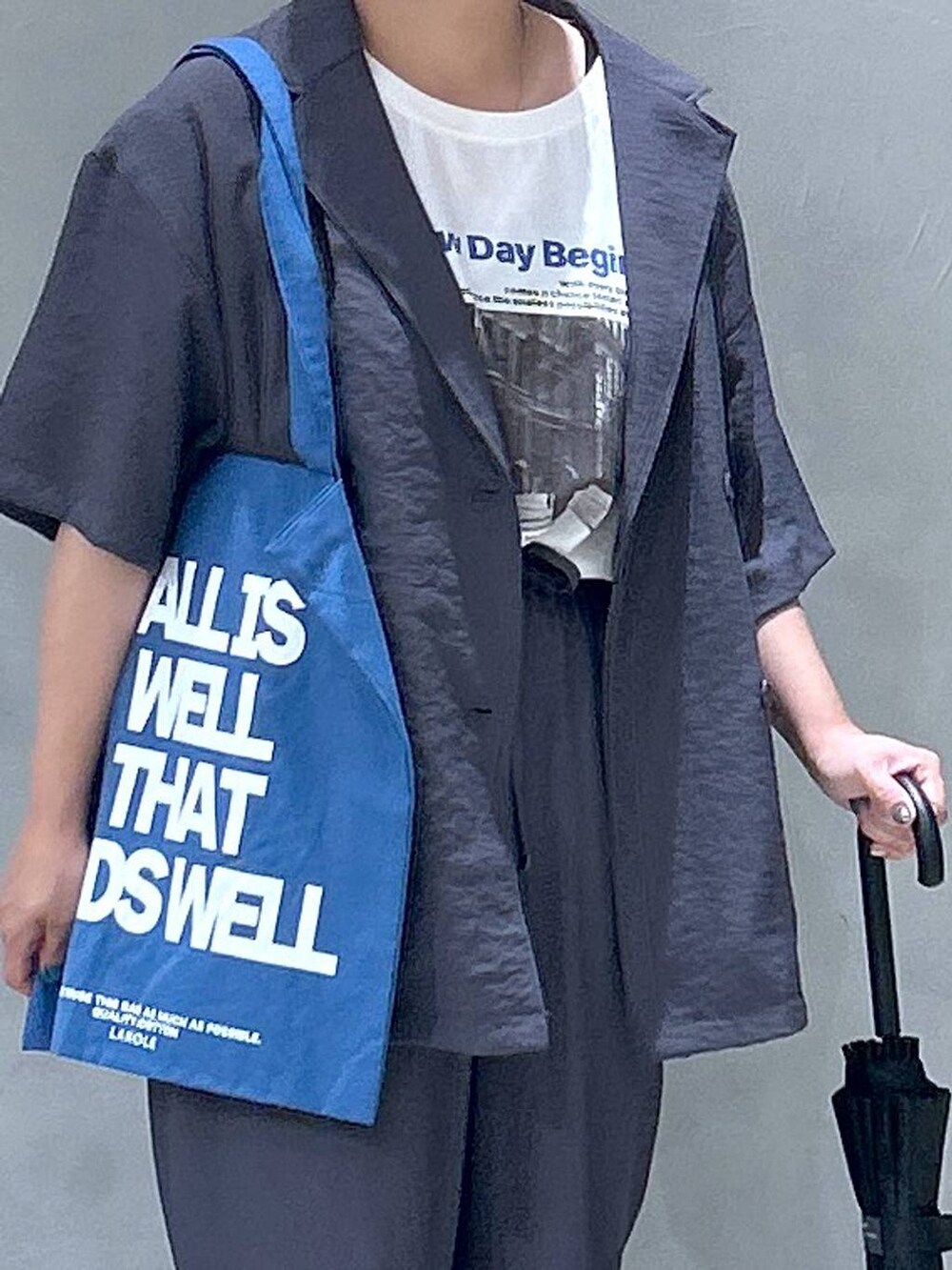 ブラック系のサンダル、ブルー系のトートバッグ、ベージュ系のテーラードジャケットを着用したレディースの夏コーディネートの3枚目の写真