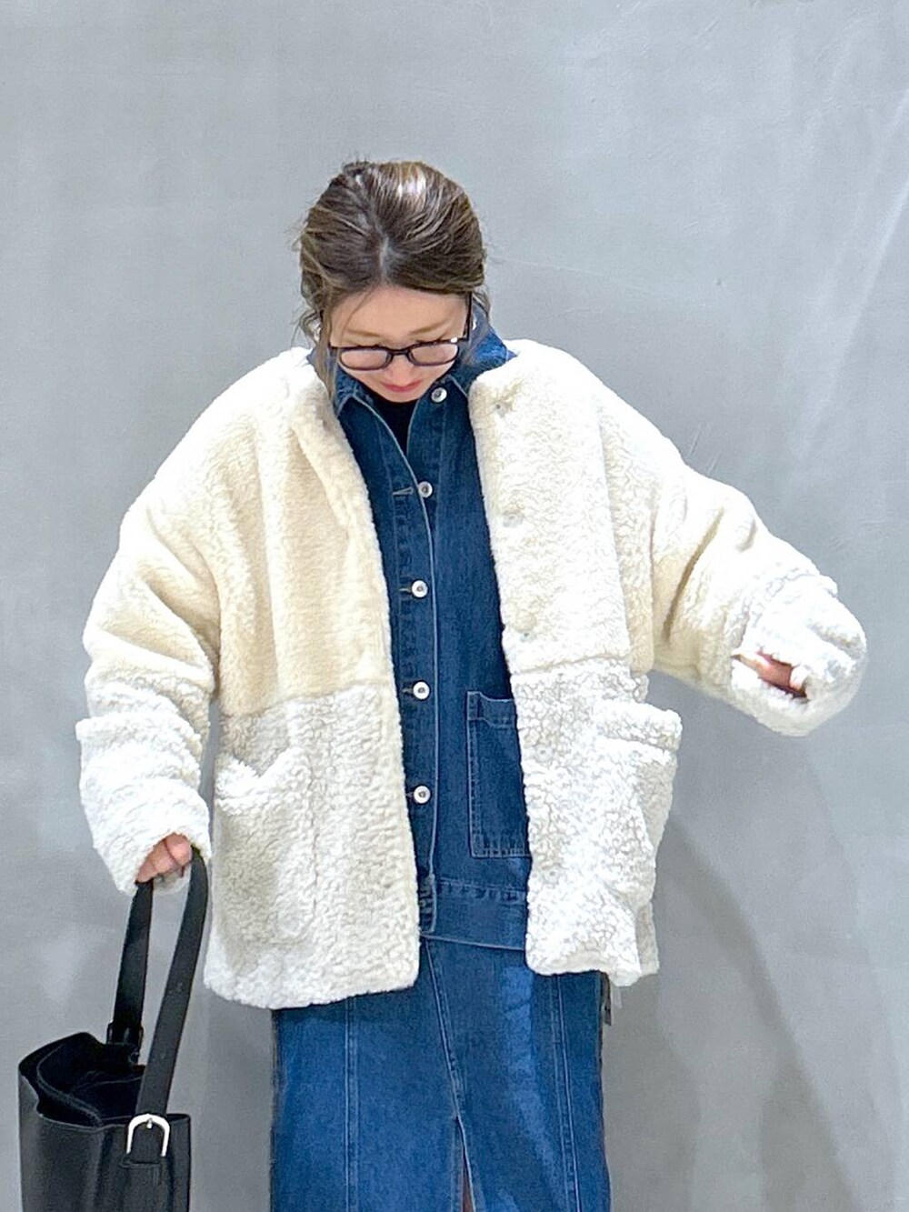 ベージュ系のブルゾン、ブルー系のデニムスカート、ブラック系のショルダーバッグを着用したレディースの冬コーディネートの3枚目の写真