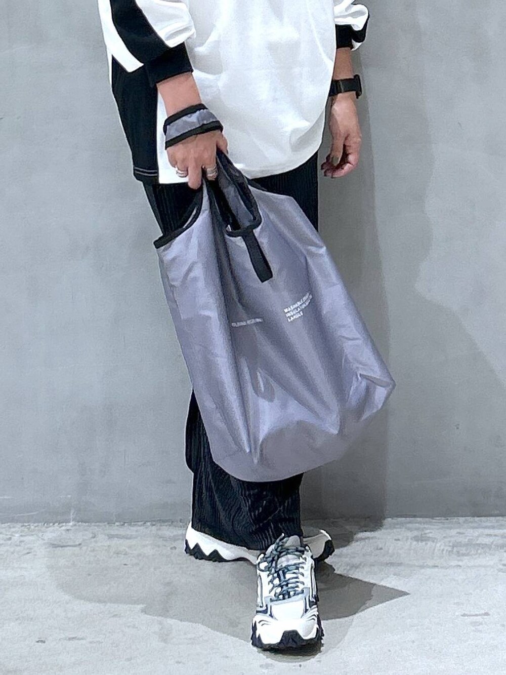 ホワイト系のスニーカー、ブラック系のスカート、グレー系のエコバッグ/サブバッグを着用したレディースの秋コーディネートの4枚目の写真