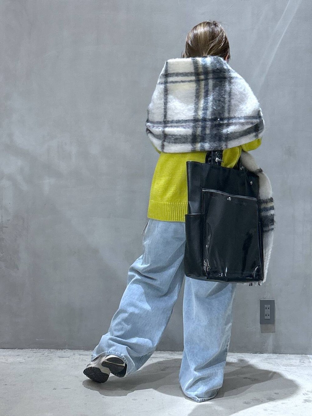 ブルー系のデニムパンツ、グリーン系のニット/セーター、ブラック系のトートバッグを着用したレディースの冬コーディネートの2枚目の写真