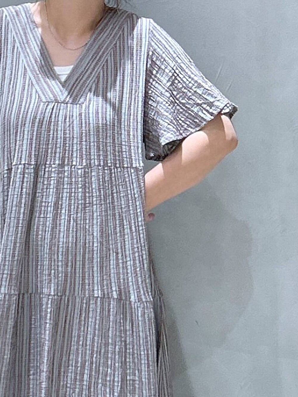 グレー系のワンピース、ブルー系のデニムパンツ、ブルー系のショルダーバッグを着用したレディースの夏コーディネートの2枚目の写真