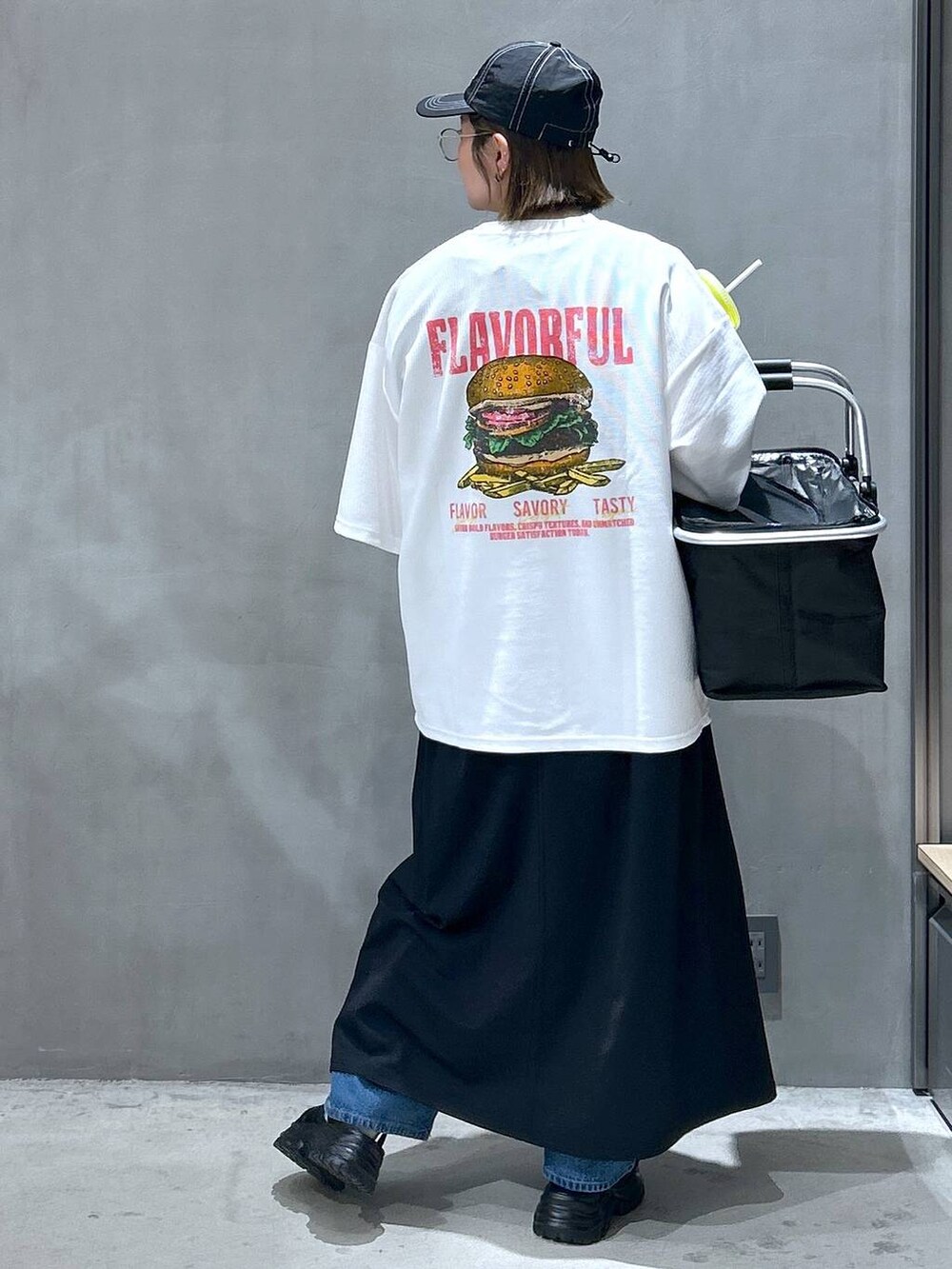 ブルー系のデニムパンツ、ブラック系のスニーカー、ブラック系のワンピースを着用したレディースの春コーディネートの2枚目の写真