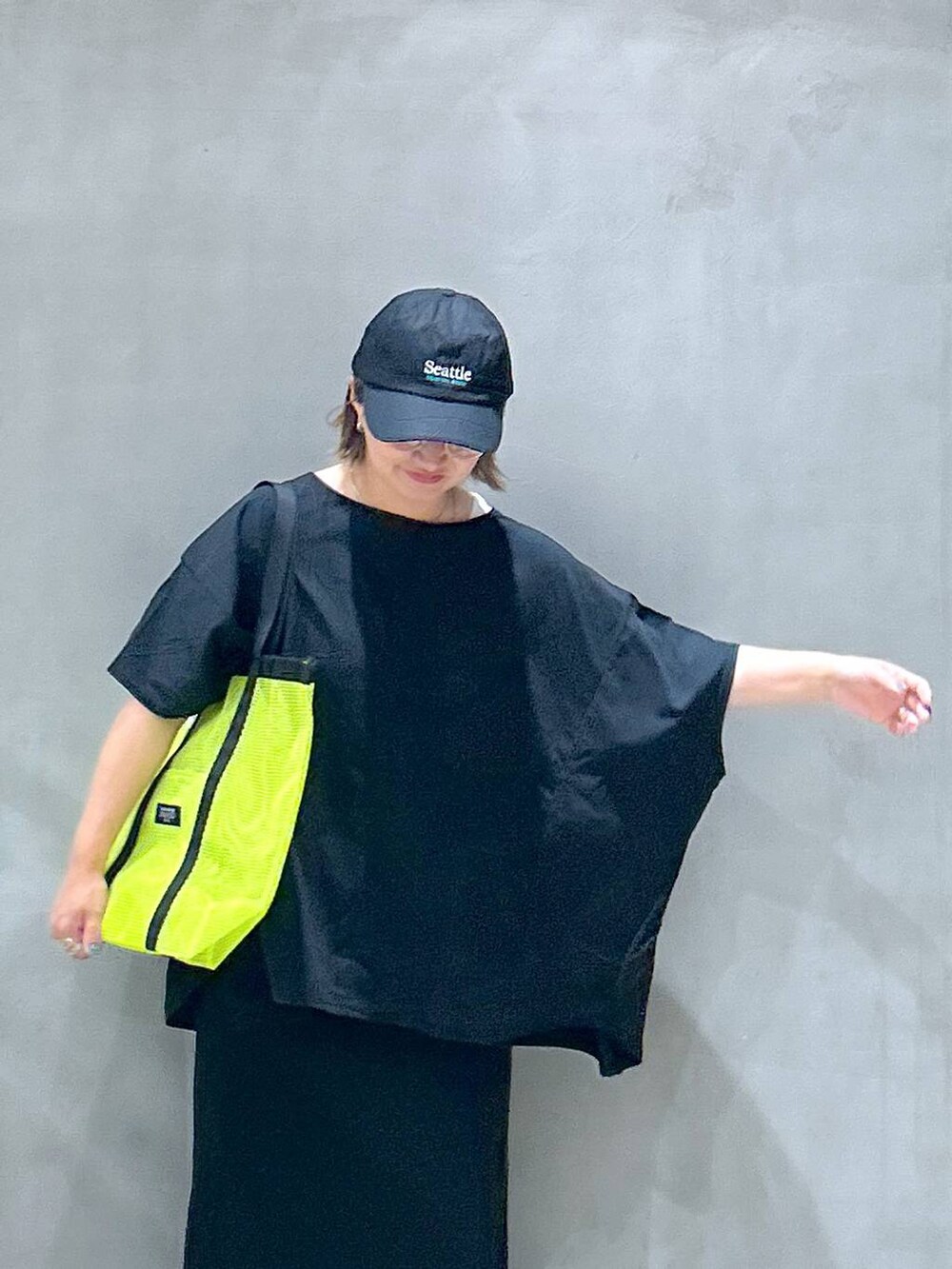 イエロー系のトートバッグ、ブラック系のスカート、ブラック系のサンダルを着用したレディースの夏コーディネートの3枚目の写真