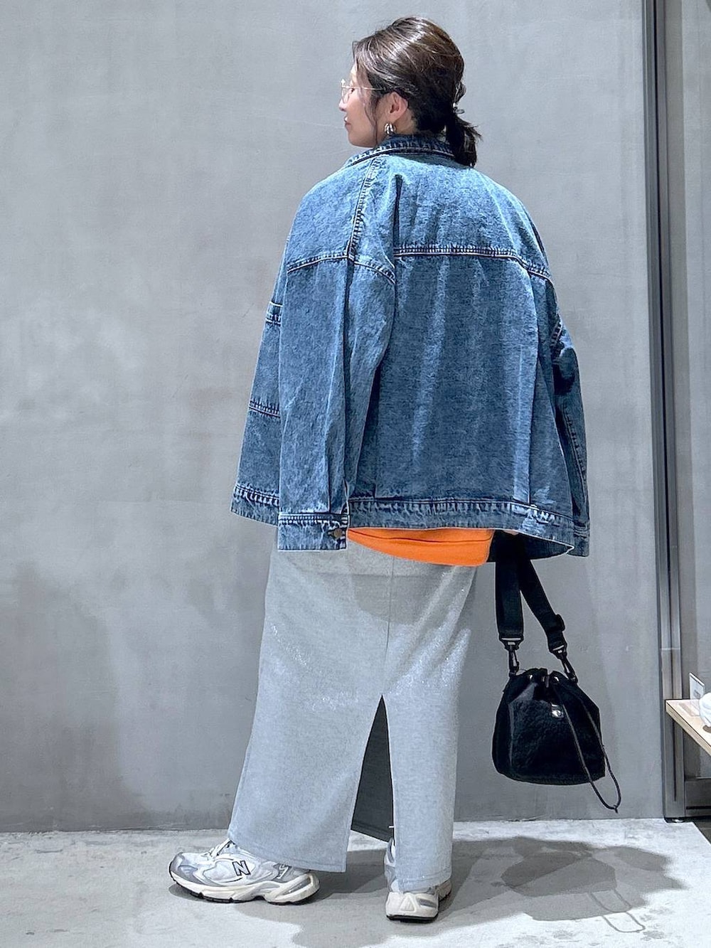 グレー系のスニーカー、ブラック系のショルダーバッグ、ブルー系のデニムジャケットを着用したレディースの秋コーディネートの2枚目の写真