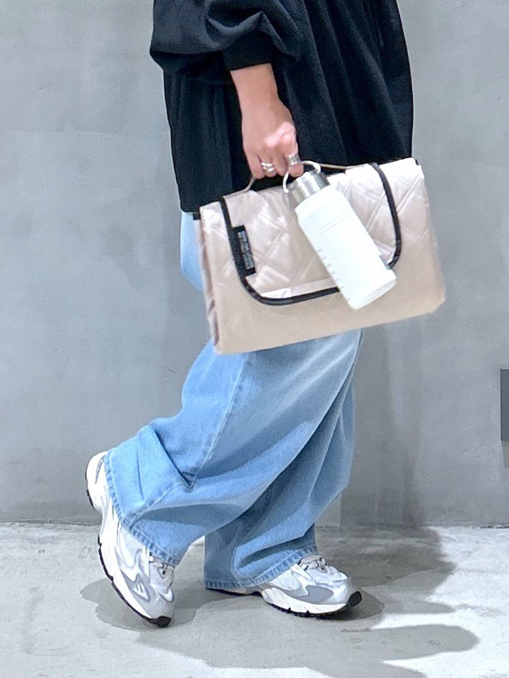 グレー系のスニーカー、ブルー系のデニムパンツ、ブラック系のチュニックを着用したレディースの秋コーディネートの4枚目の写真