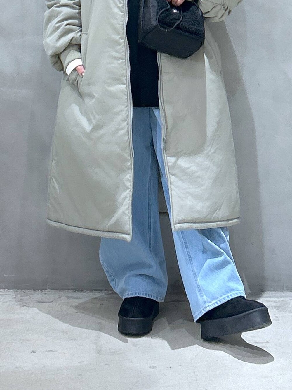 ブラック系のショルダーバッグ、ブラック系のスリッポン、ブルー系のデニムパンツを着用したレディースの冬コーディネートの3枚目の写真