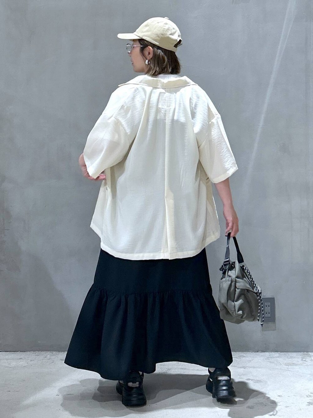 ブラック系のスニーカー、グリーン系のショルダーバッグ、ホワイト系のTシャツ/カットソーを着用したレディースの春コーディネートの2枚目の写真