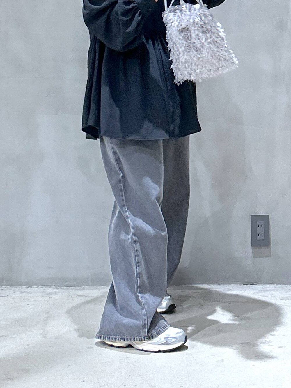 グレー系のスニーカー、ブラック系のデニムパンツ、グレー系のショルダーバッグを着用したレディースの夏コーディネートの4枚目の写真