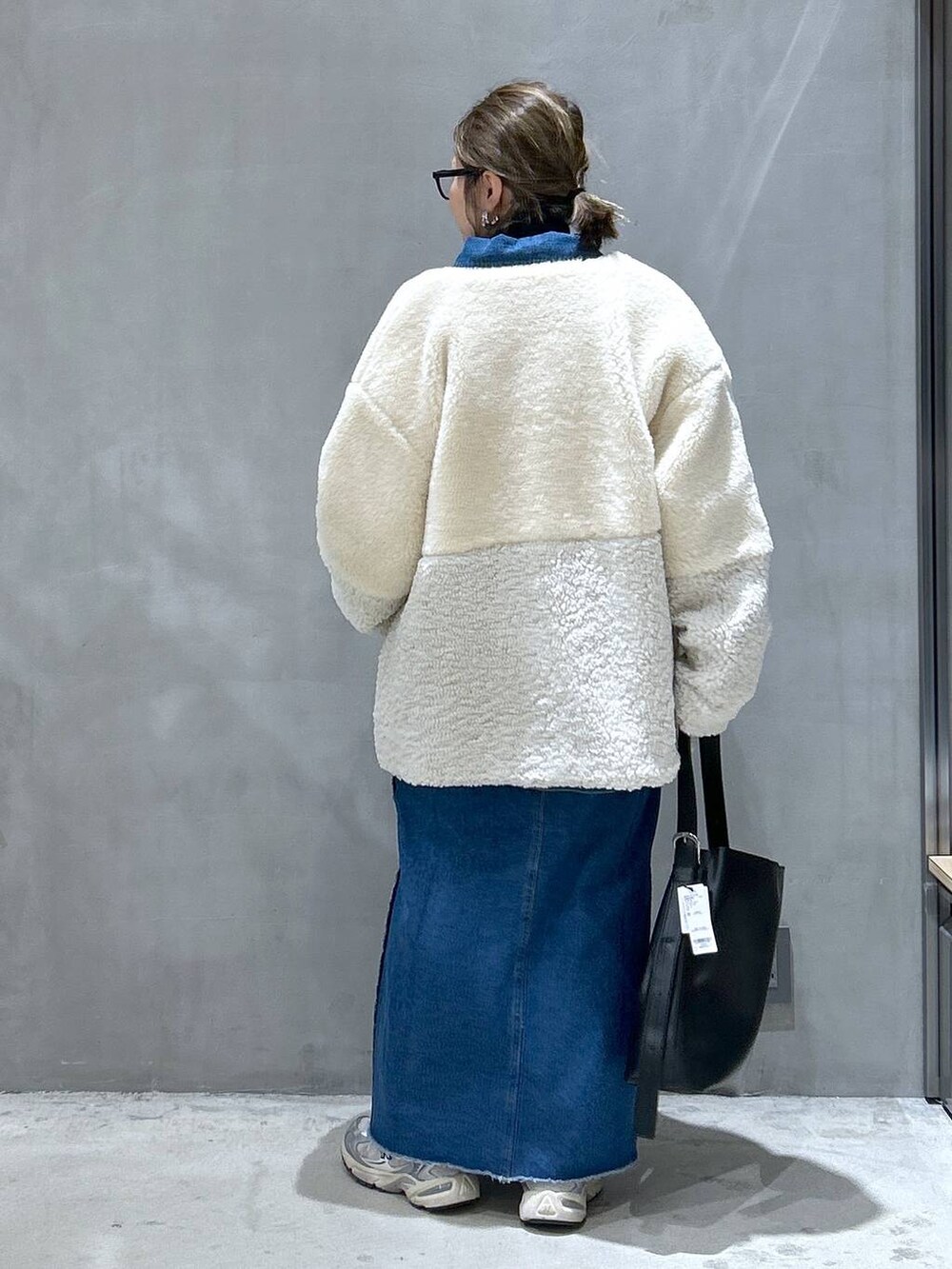 ベージュ系のブルゾン、ブルー系のデニムスカート、ブラック系のショルダーバッグを着用したレディースの冬コーディネートの2枚目の写真