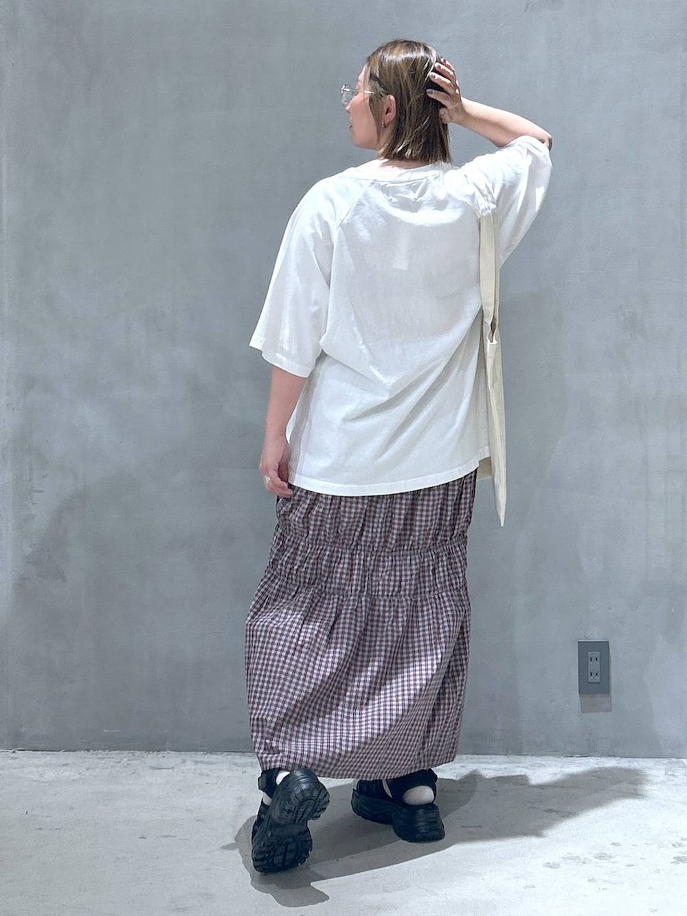 ブラック系のスニーカー、オレンジ系のスカート、ホワイト系のTシャツ/カットソーを着用したレディースの春コーディネートの5枚目の写真