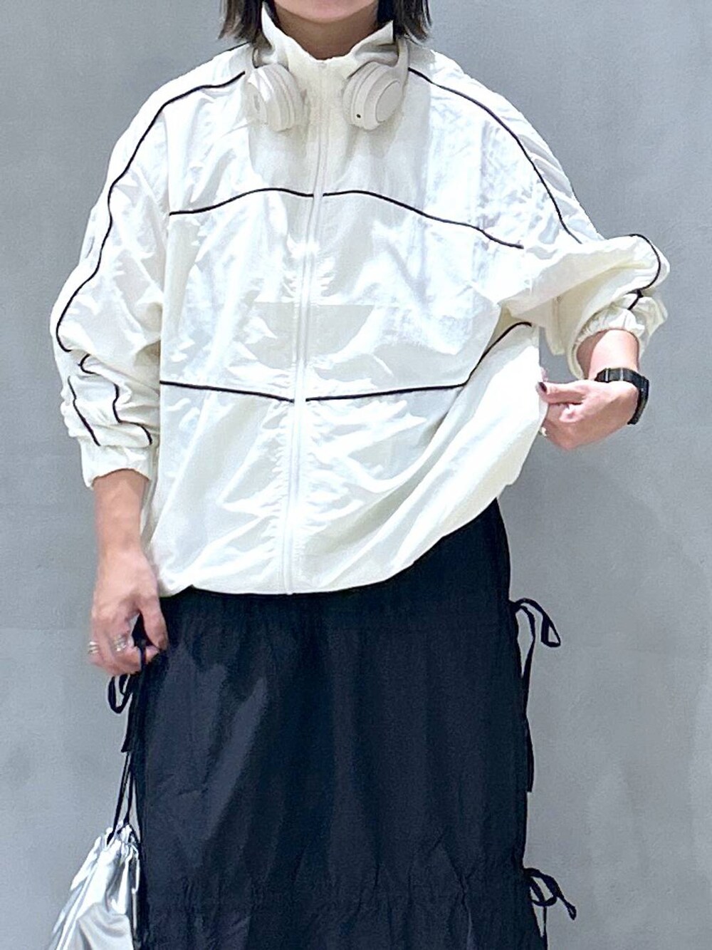 グレー系のスニーカー、ベージュ系のブルゾン、ブラック系のスカートを着用したレディースの秋コーディネートの3枚目の写真