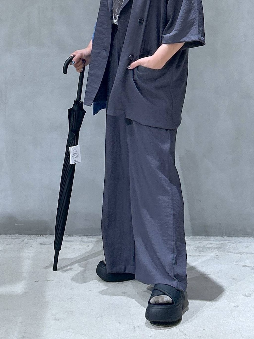 ブラック系のサンダル、ブルー系のトートバッグ、ベージュ系のテーラードジャケットを着用したレディースの夏コーディネートの4枚目の写真