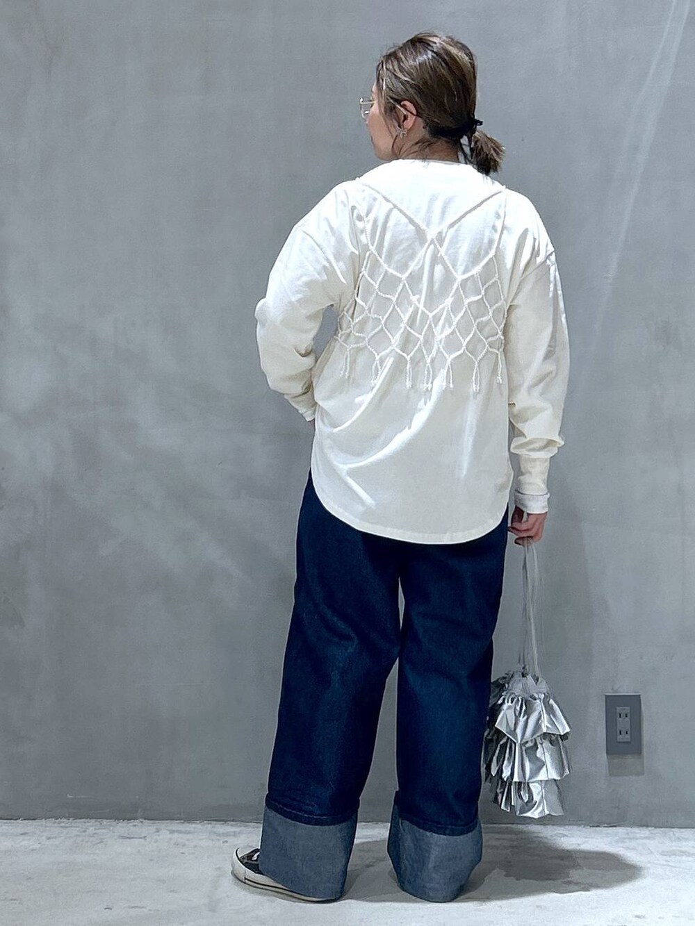 ホワイト系のベスト、シルバー系のショルダーバッグ、ブルー系のデニムパンツを着用したレディースの冬コーディネートの2枚目の写真