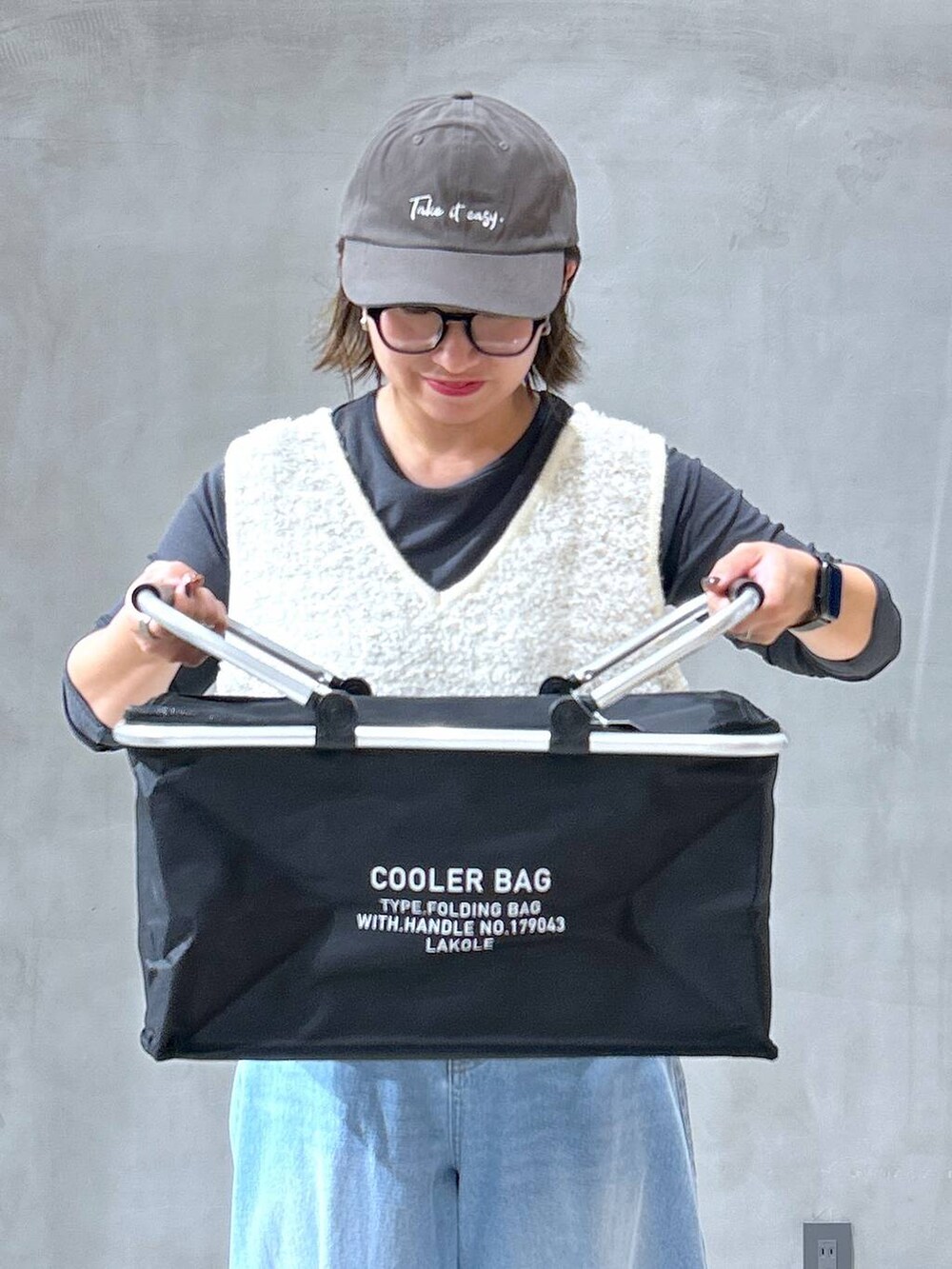 グレー系のスニーカー、ブルー系のデニムパンツ、ベージュ系のベストを着用したレディースの秋コーディネートの3枚目の写真