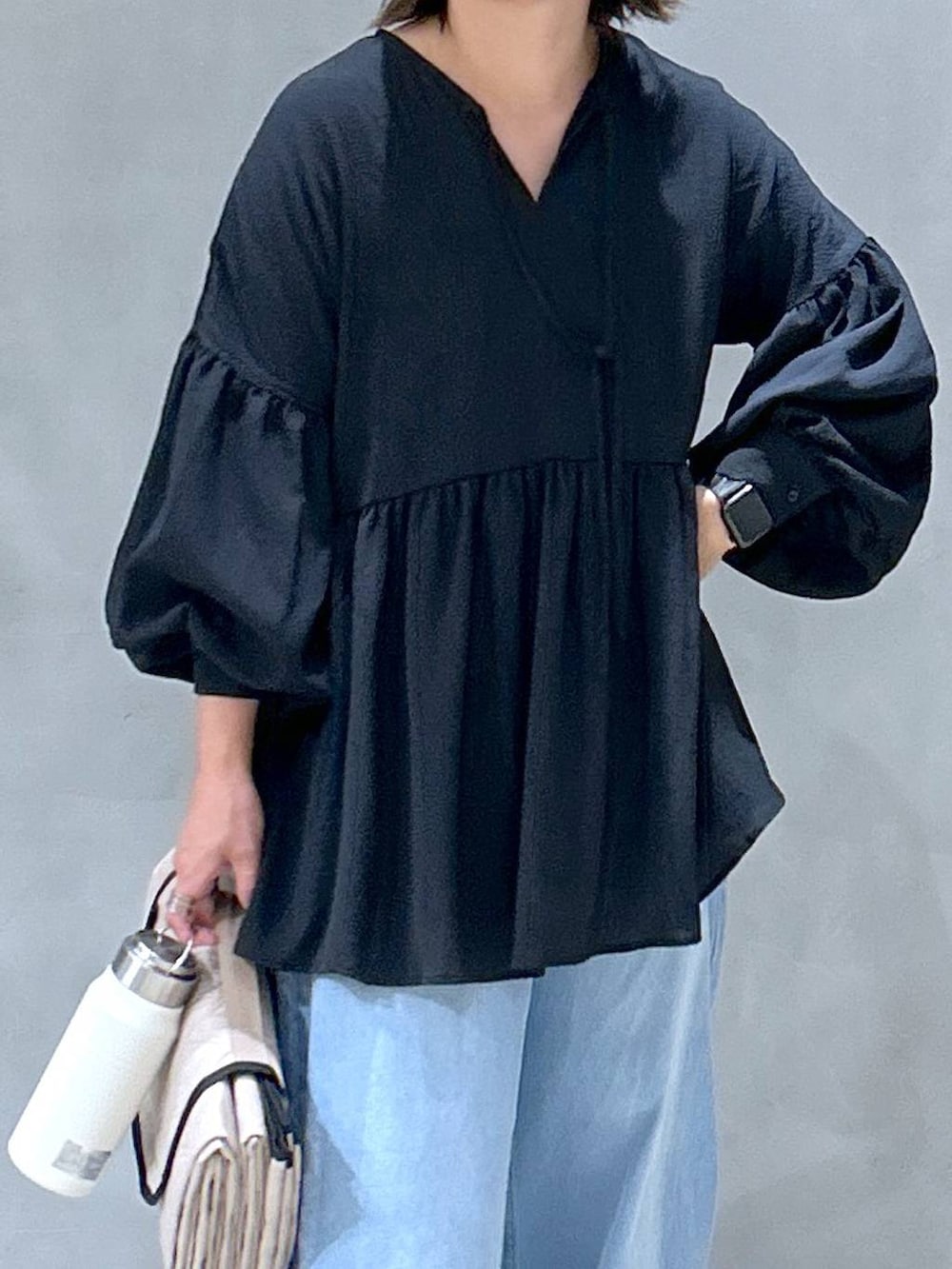 グレー系のスニーカー、ブルー系のデニムパンツ、ブラック系のチュニックを着用したレディースの秋コーディネートの3枚目の写真