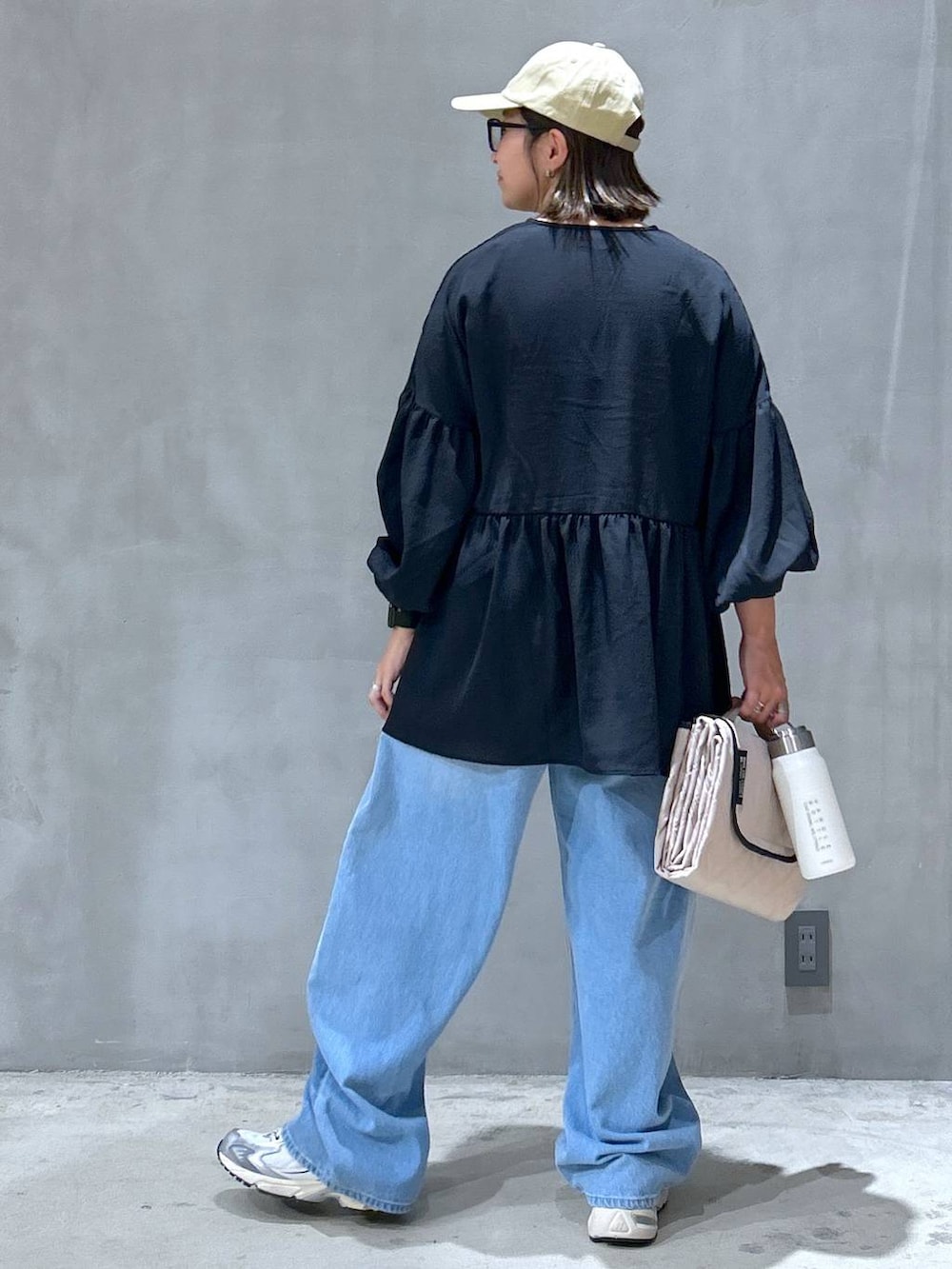 グレー系のスニーカー、ブルー系のデニムパンツ、ブラック系のチュニックを着用したレディースの秋コーディネートの2枚目の写真