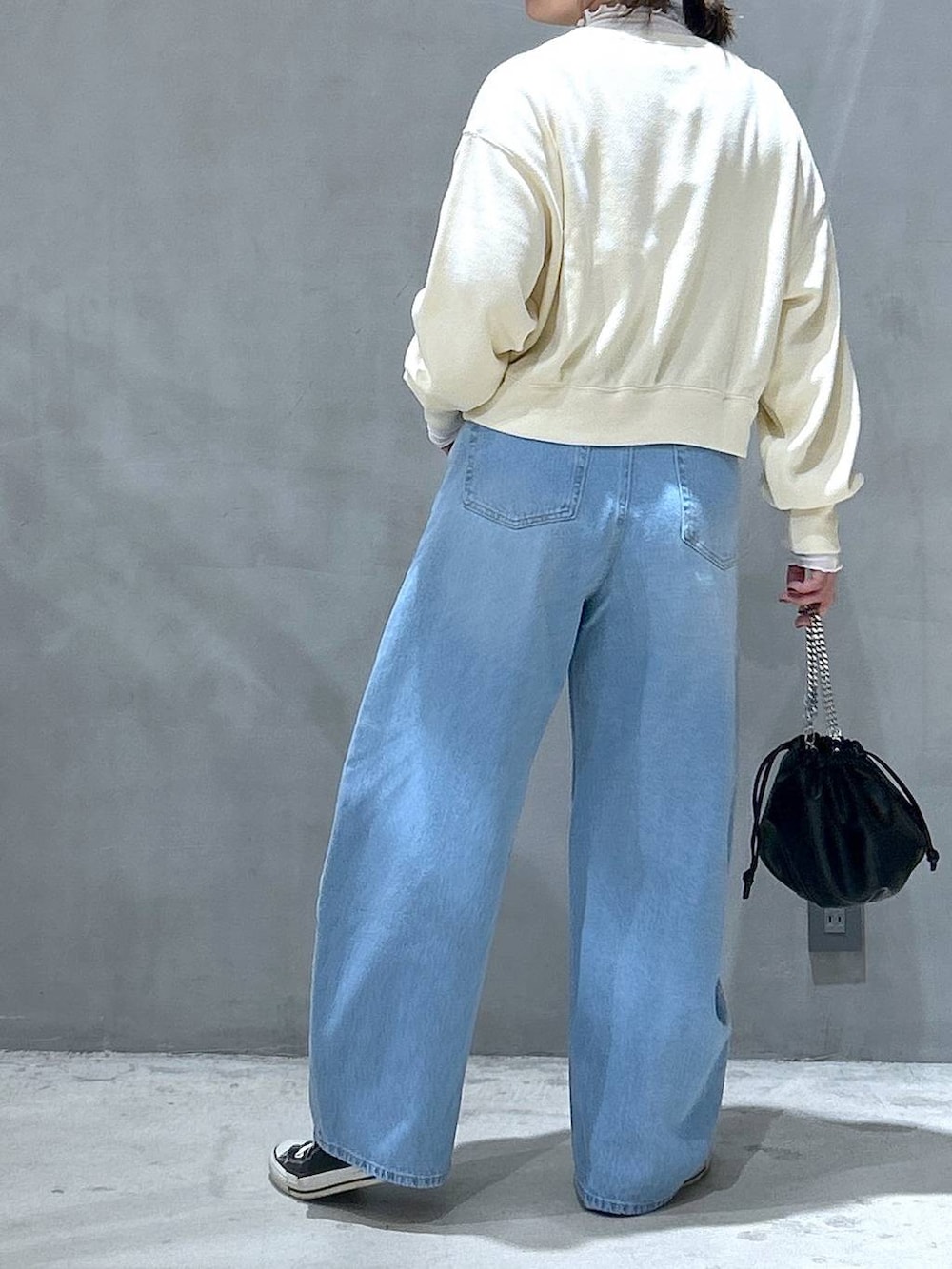 ブルー系のデニムパンツ、ベージュ系のTシャツ/カットソー、ブラック系のショルダーバッグを着用したレディースの冬コーディネートの2枚目の写真