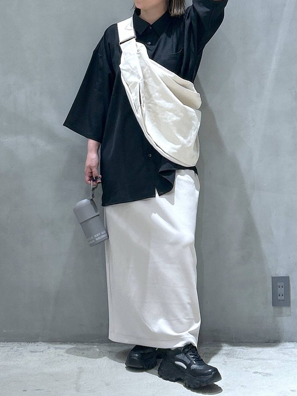 ベージュ系のショルダーバッグ、ブラック系のスニーカー、ベージュ系のスカートを着用したレディースの春コーディネートの3枚目の写真