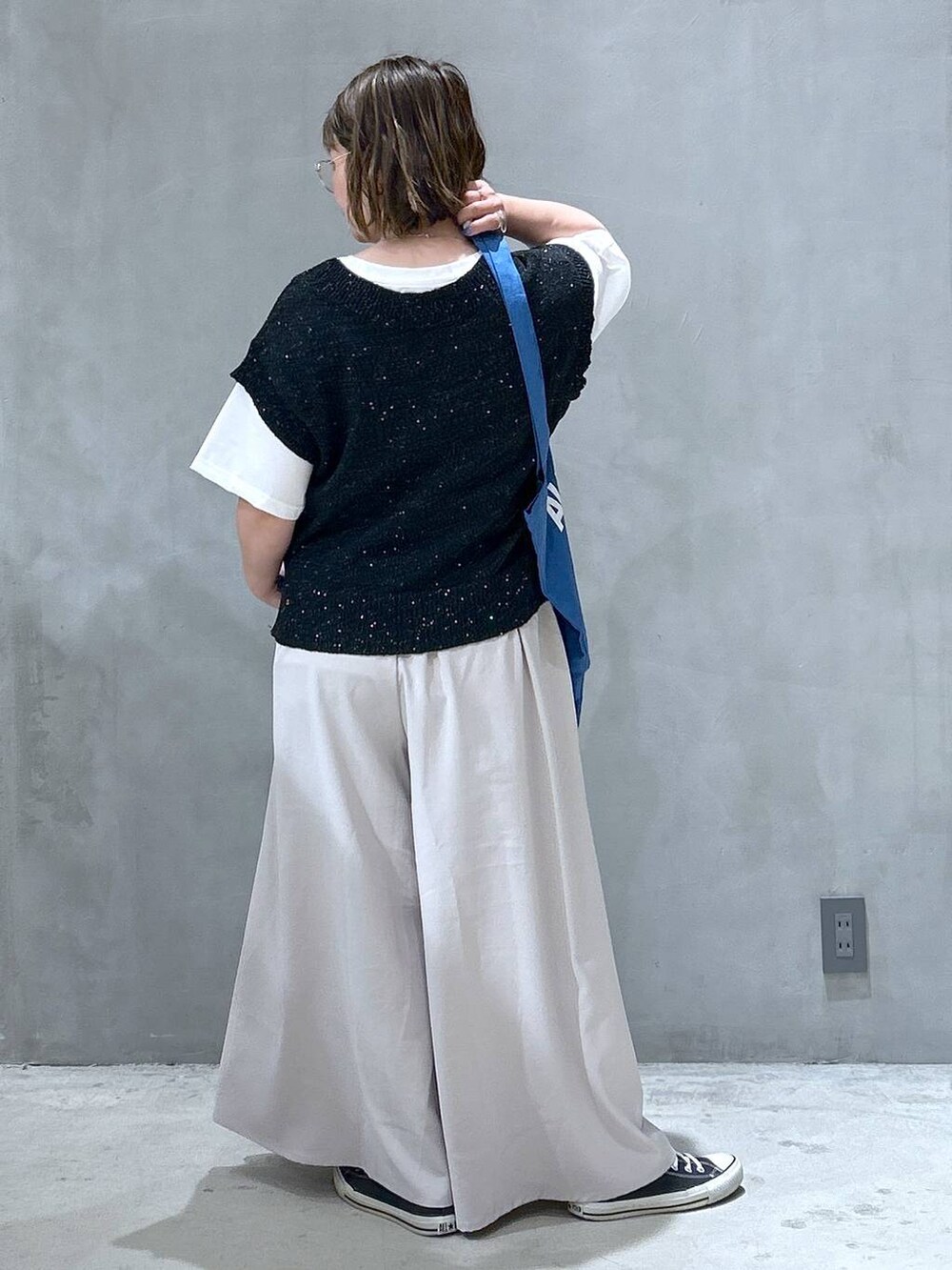 ブルー系のトートバッグ、ブラック系のベスト、グレー系のその他パンツを着用したレディースの夏コーディネートの2枚目の写真