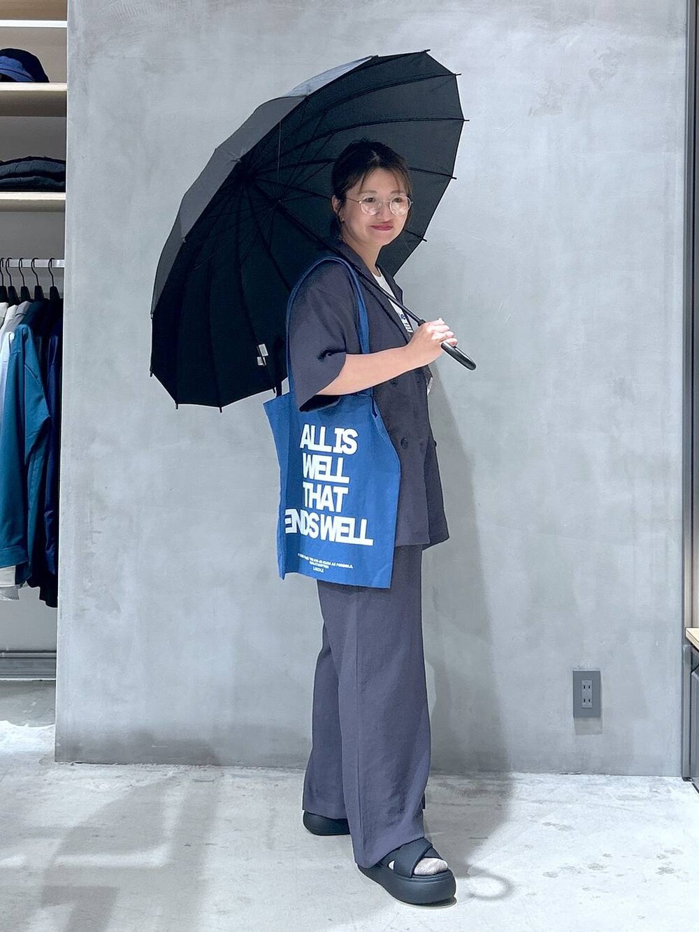 ブラック系のサンダル、ブルー系のトートバッグ、ベージュ系のテーラードジャケットを着用したレディースの夏コーディネートの7枚目の写真