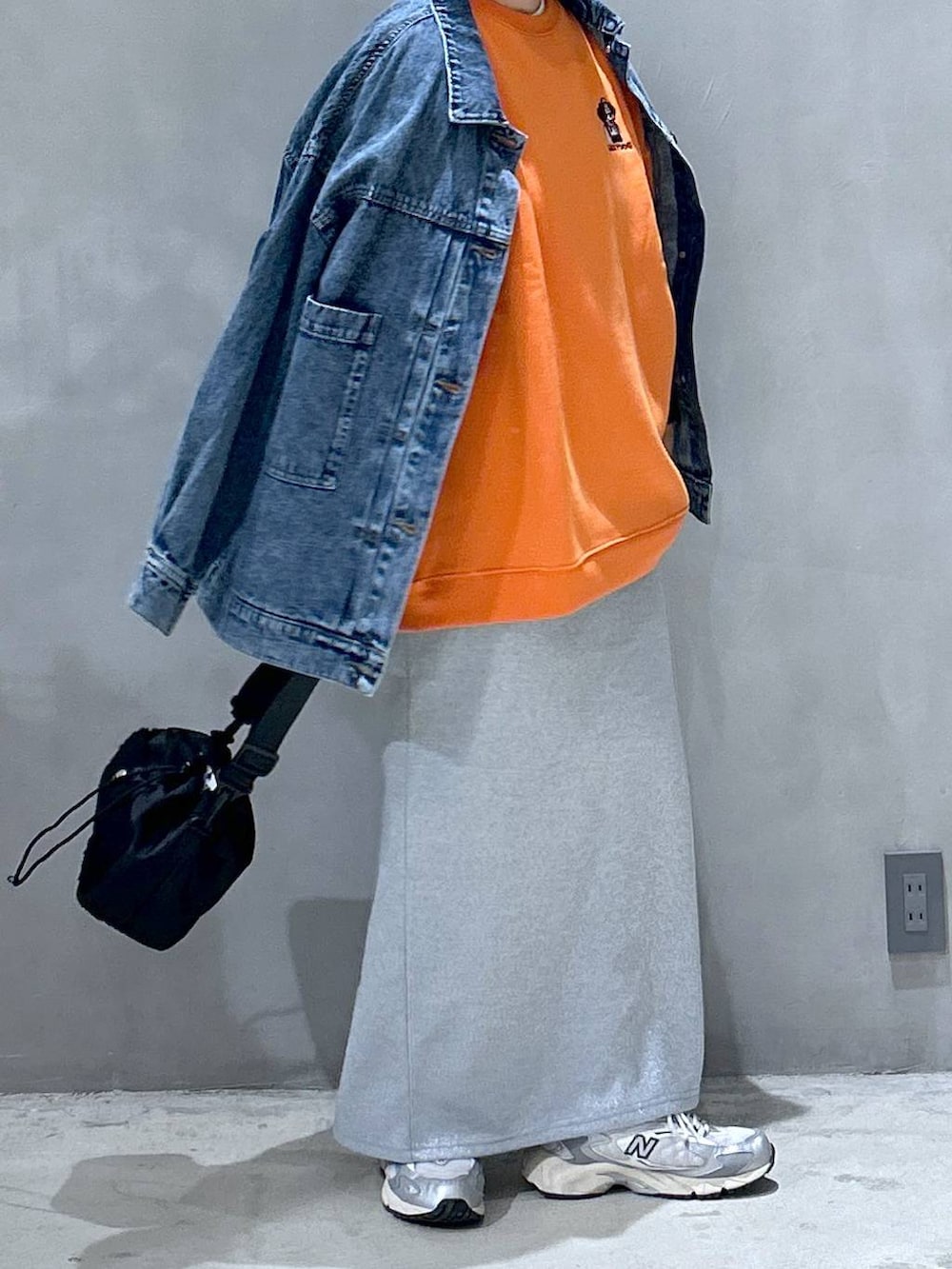 グレー系のスニーカー、ブラック系のショルダーバッグ、ブルー系のデニムジャケットを着用したレディースの秋コーディネートの4枚目の写真