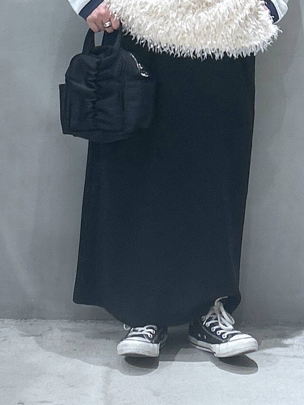 ブラック系のスカート、ホワイト系のベスト、ベージュ系のTシャツ/カットソーを着用したレディースの春コーディネートの3枚目の写真