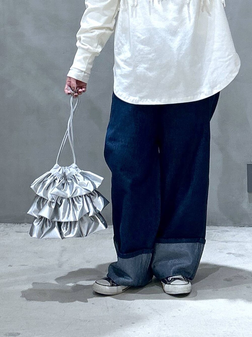 ホワイト系のベスト、シルバー系のショルダーバッグ、ブルー系のデニムパンツを着用したレディースの冬コーディネートの4枚目の写真