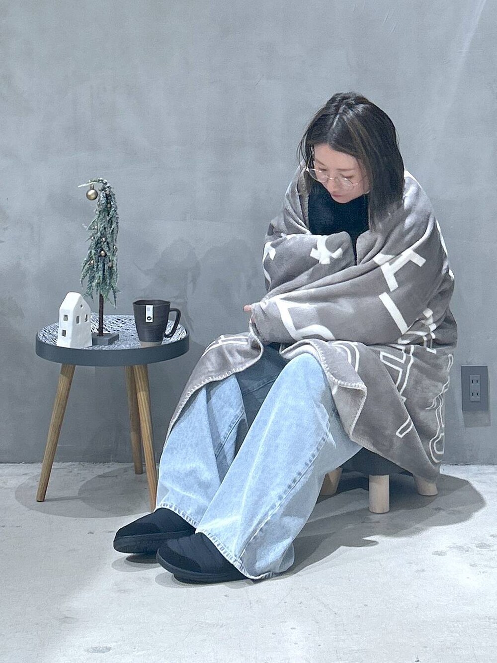 ブラック系のニット/セーター、ブルー系のデニムパンツ、ブラック系のスニーカーを着用したレディースの秋コーディネートの4枚目の写真