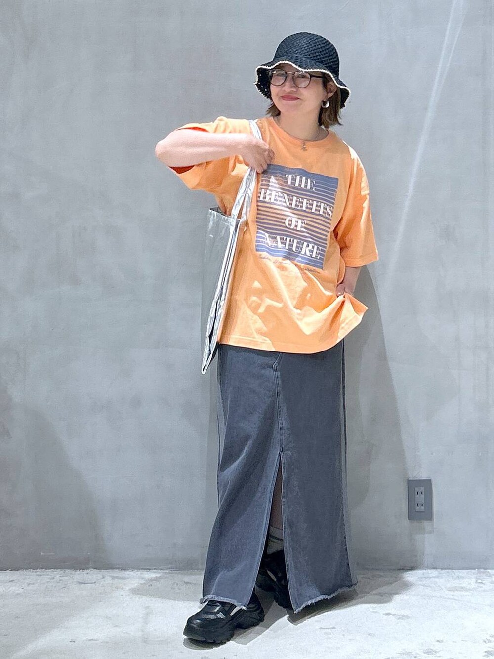 ブラック系のスニーカー、ブラック系のデニムスカート、オレンジ系のTシャツ/カットソーを着用したレディースの春コーディネートの5枚目の写真