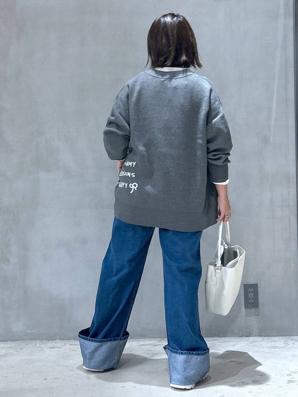 ホワイト系のスニーカー、ブルー系のデニムパンツ、ホワイト系のショルダーバッグを着用したレディースの秋コーディネートの2枚目の写真