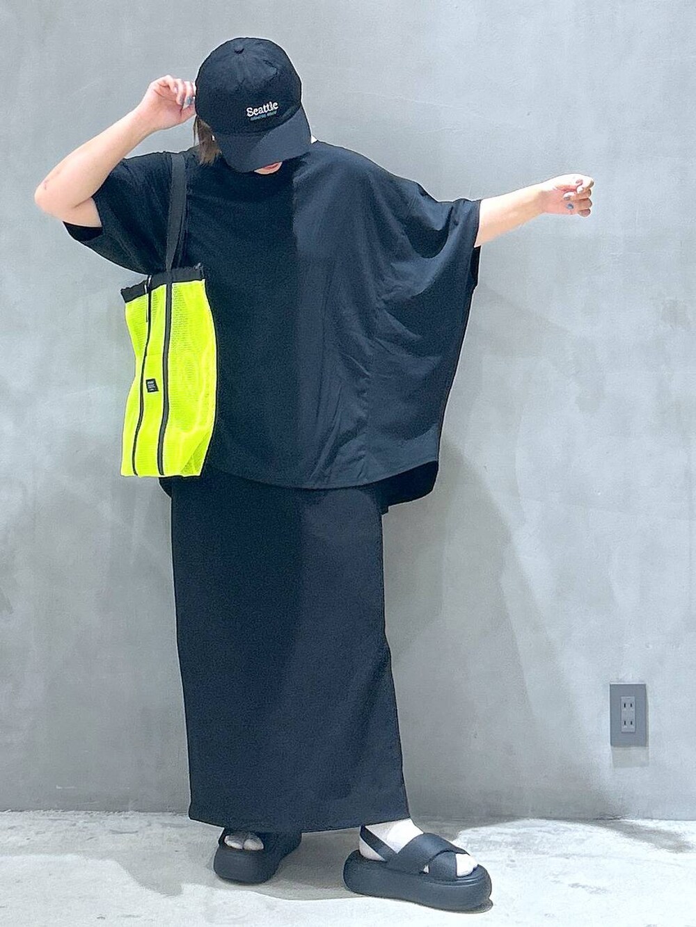 イエロー系のトートバッグ、ブラック系のスカート、ブラック系のサンダルを着用したレディースの夏コーディネートの7枚目の写真