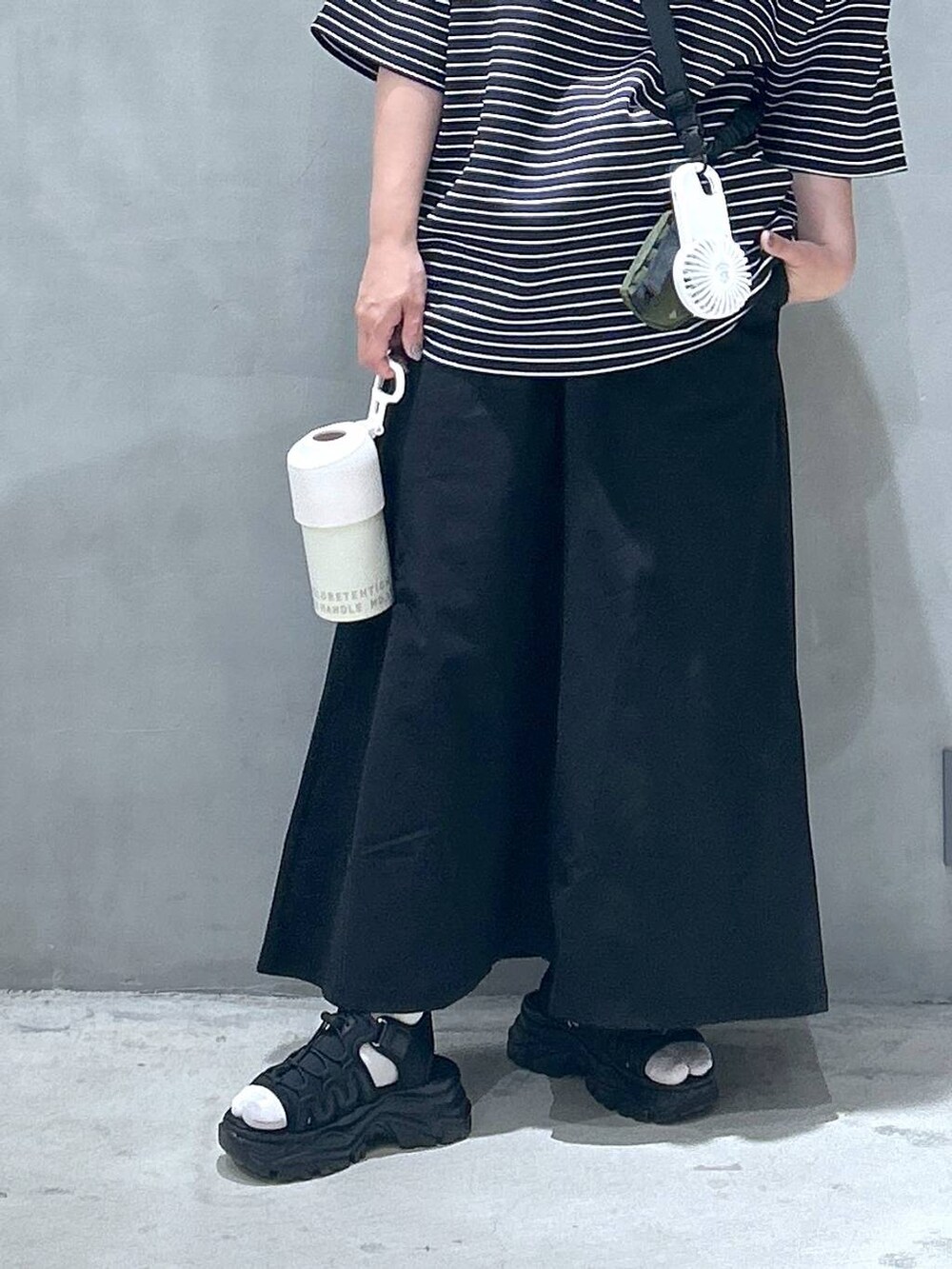 グリーン系のショルダーバッグ、ブラック系のスニーカー、ブラック系のスカートを着用したレディースの春コーディネートの4枚目の写真