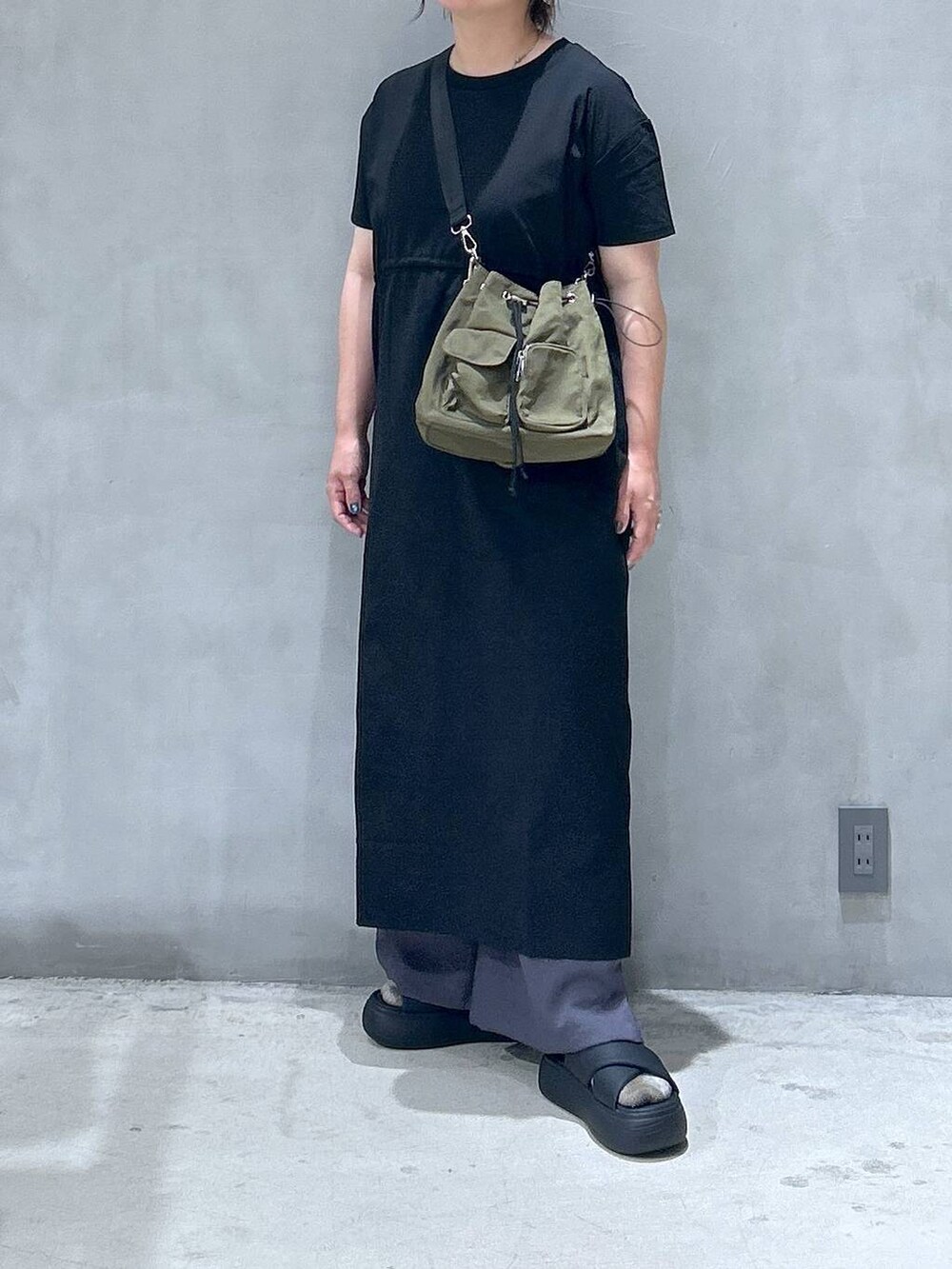 ブラック系のサンダル、グリーン系のショルダーバッグ、ブラック系のワンピースを着用したレディースの夏コーディネートの5枚目の写真