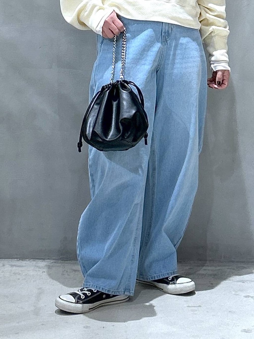 ブルー系のデニムパンツ、ベージュ系のTシャツ/カットソー、ブラック系のショルダーバッグを着用したレディースの冬コーディネートの4枚目の写真