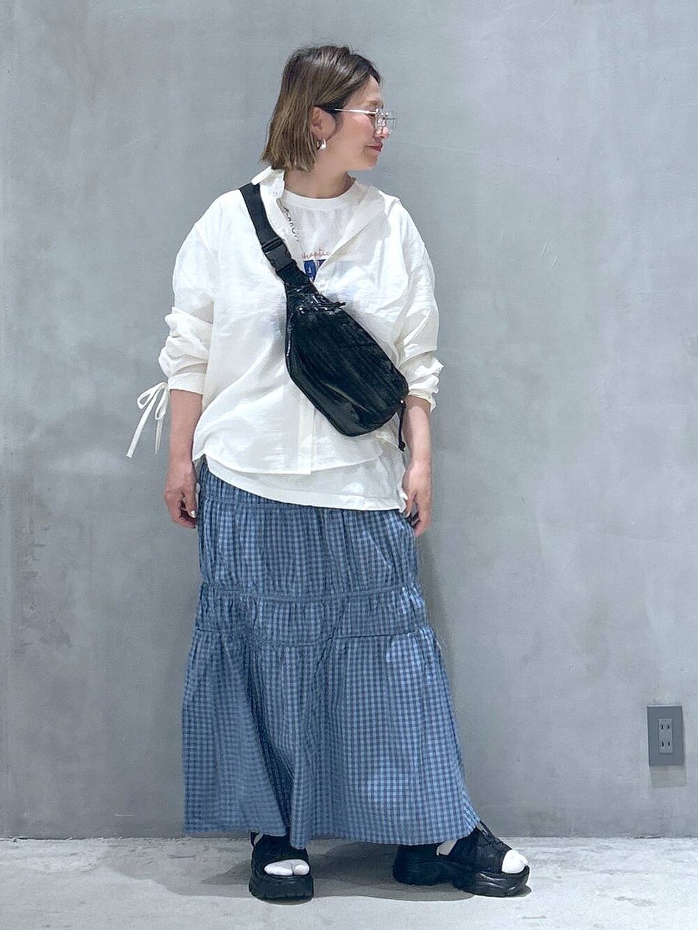 ブラック系のボディバッグ/ウエストポーチ、ブラック系のスニーカー、ホワイト系のシャツ/ブラウスを着用したレディースの春コーディネートの3枚目の写真