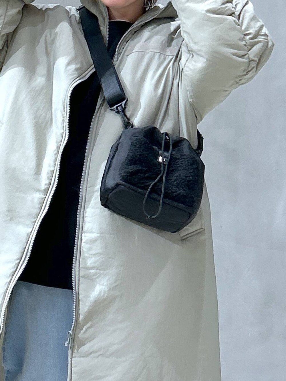 ブラック系のショルダーバッグ、ブラック系のスリッポン、ブルー系のデニムパンツを着用したレディースの冬コーディネートの2枚目の写真