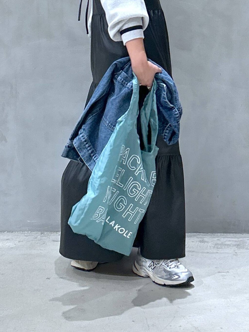 グレー系のスニーカー、ブラック系のワンピース、ブルー系のデニムジャケットを着用したレディースの秋コーディネートの4枚目の写真