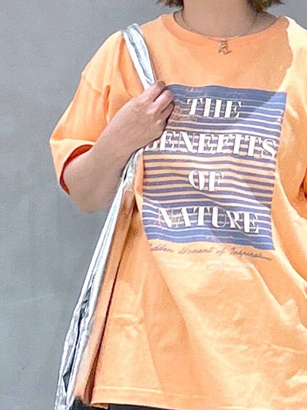 ブラック系のスニーカー、ブラック系のデニムスカート、オレンジ系のTシャツ/カットソーを着用したレディースの春コーディネートの3枚目の写真