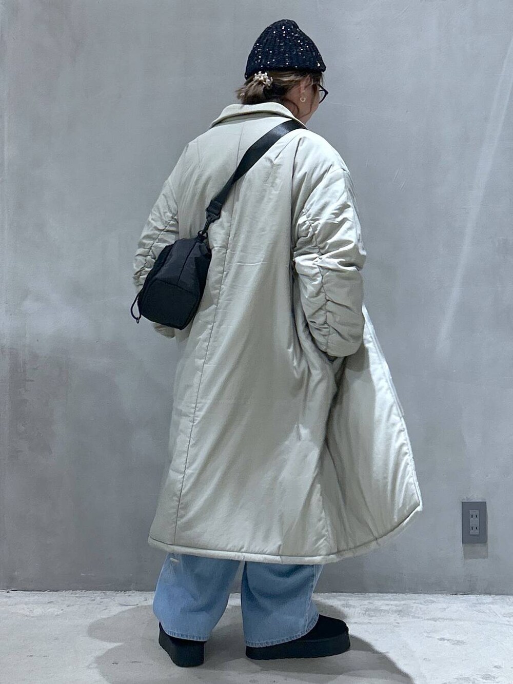 ブラック系のショルダーバッグ、ブラック系のスリッポン、ブルー系のデニムパンツを着用したレディースの冬コーディネートの5枚目の写真