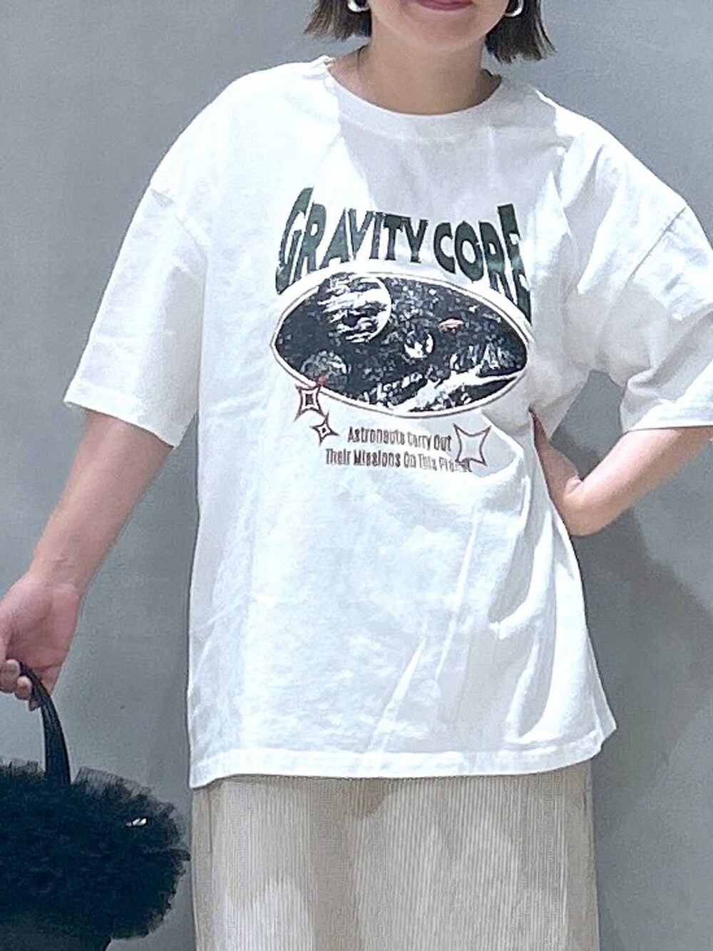 ブラック系のショルダーバッグ、ホワイト系のTシャツ/カットソー、ベージュ系のワンピースを着用したレディースの夏コーディネートの3枚目の写真