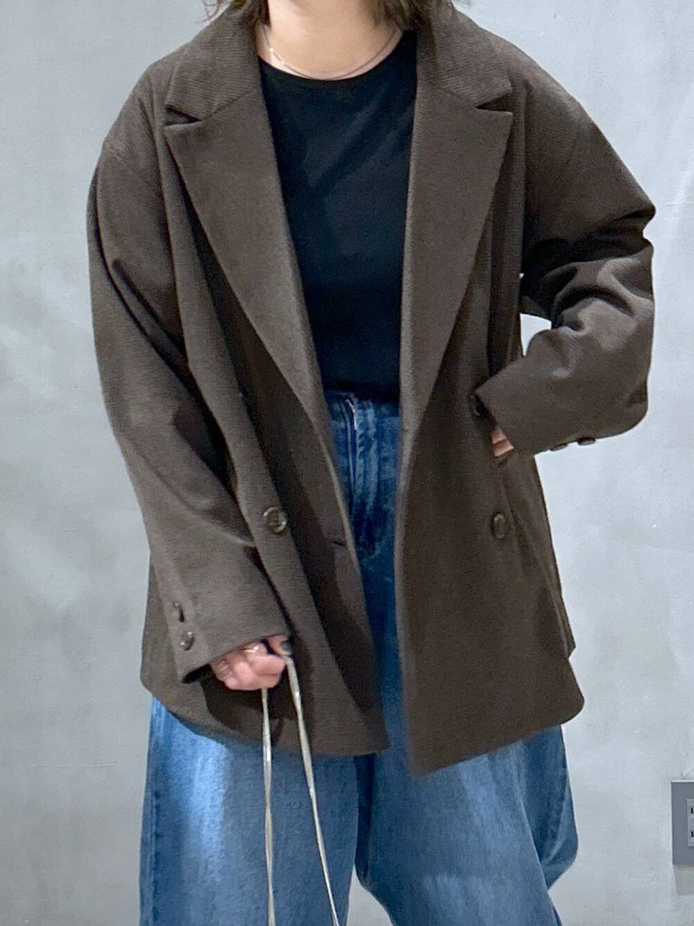 ブルー系のデニムパンツ、ブラウン系のテーラードジャケット、その他のショルダーバッグを着用したレディースの秋コーディネートの3枚目の写真