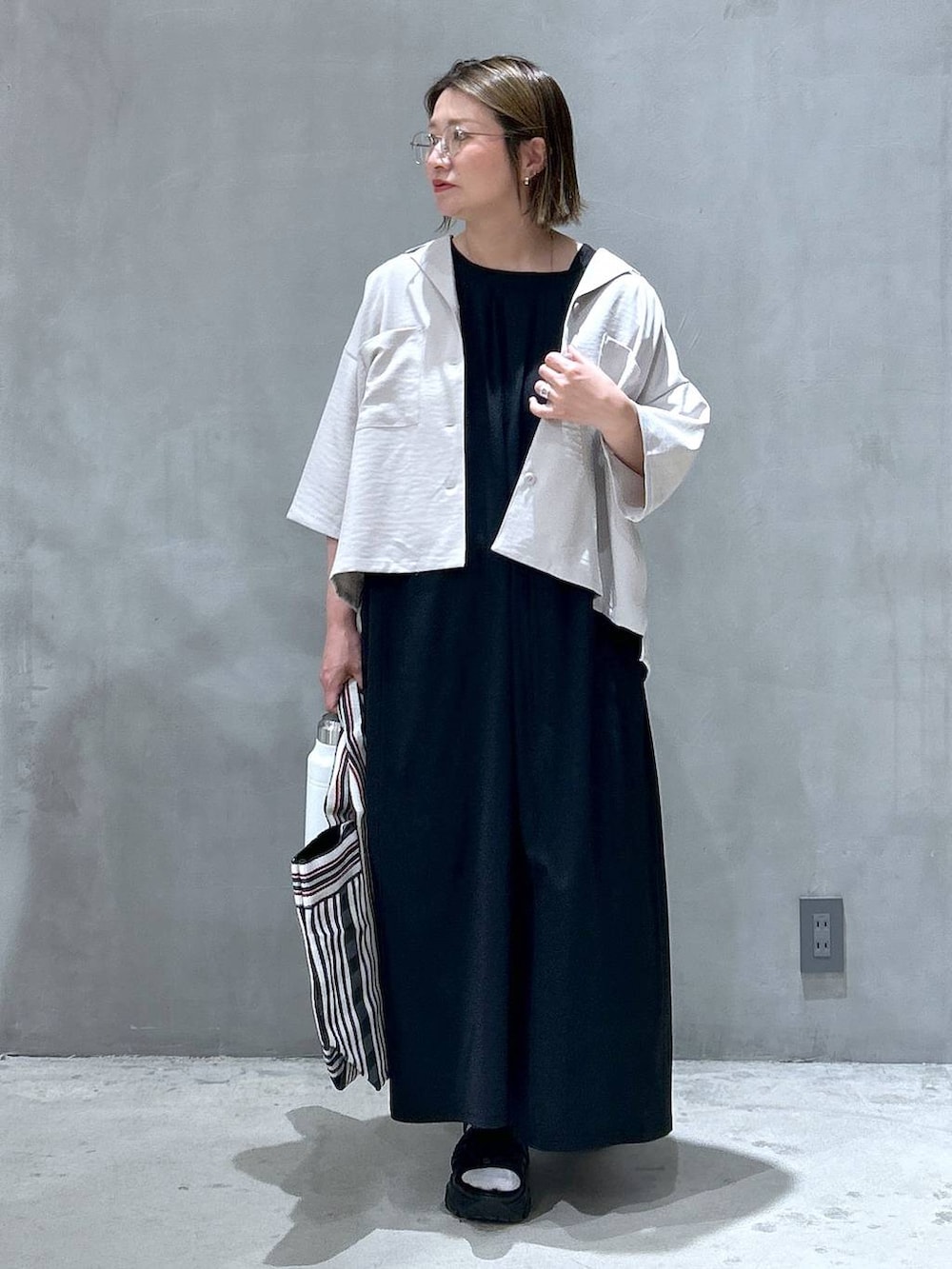 ブラック系のスニーカー、ブラック系のトートバッグ、ブラック系のワンピースを着用したレディースの春コーディネートの3枚目の写真