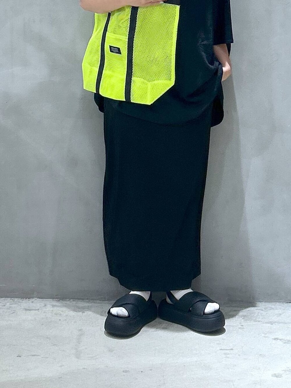 イエロー系のトートバッグ、ブラック系のスカート、ブラック系のサンダルを着用したレディースの夏コーディネートの6枚目の写真