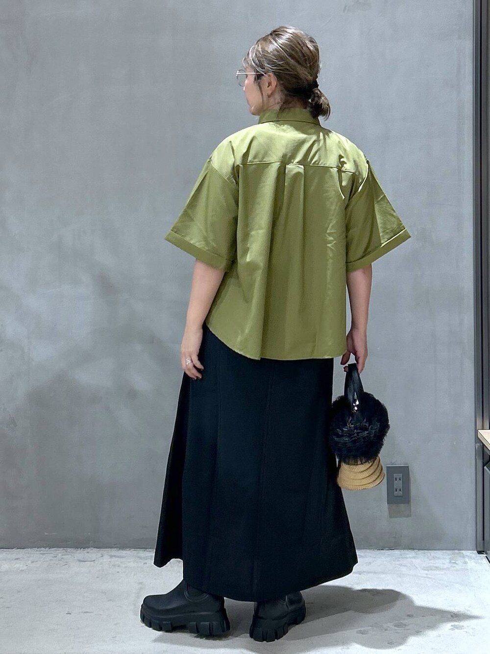 ブラック系のスカート、ベージュ系のショルダーバッグ、ブラック系のレインシューズを着用したレディースの夏コーディネートの2枚目の写真