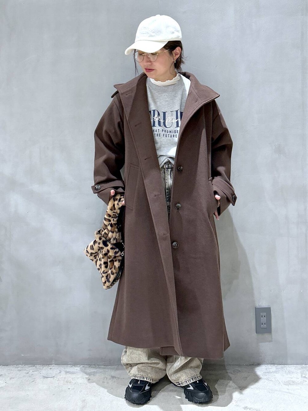 ブラウン系のステンカラーコート、グレー系のスニーカー、その他のショルダーバッグを着用したレディースの秋コーディネートの6枚目の写真