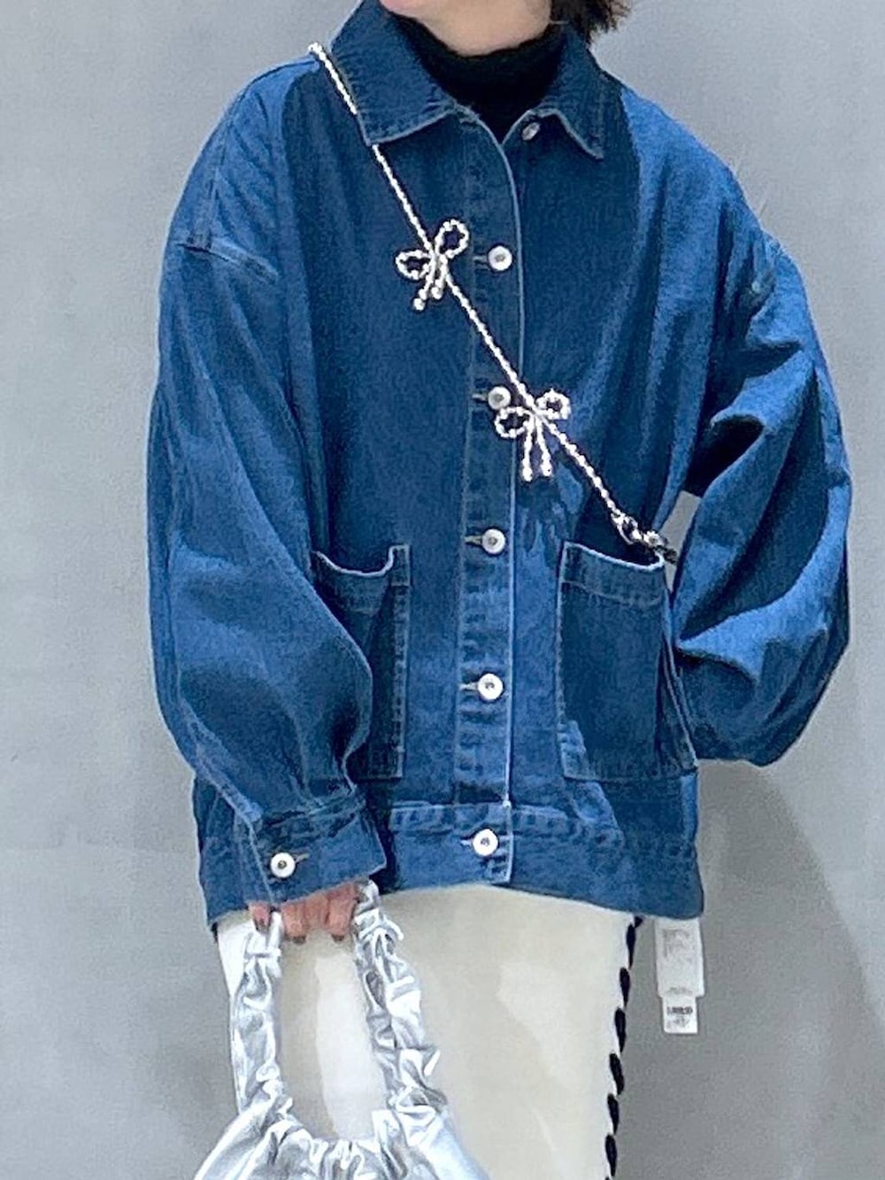 ベージュ系のスカート、シルバー系のショルダーバッグ、ブルー系のデニムジャケットを着用したレディースの冬コーディネートの3枚目の写真